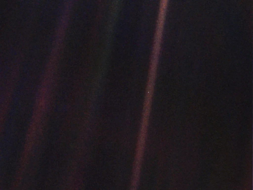L'immagine originale di Pale Blue Dot, pubblicata il 14 febbraio 1990. La Terra è visibile come un puntino luminoso all'interno del raggio di sole appena a destra del centro. 