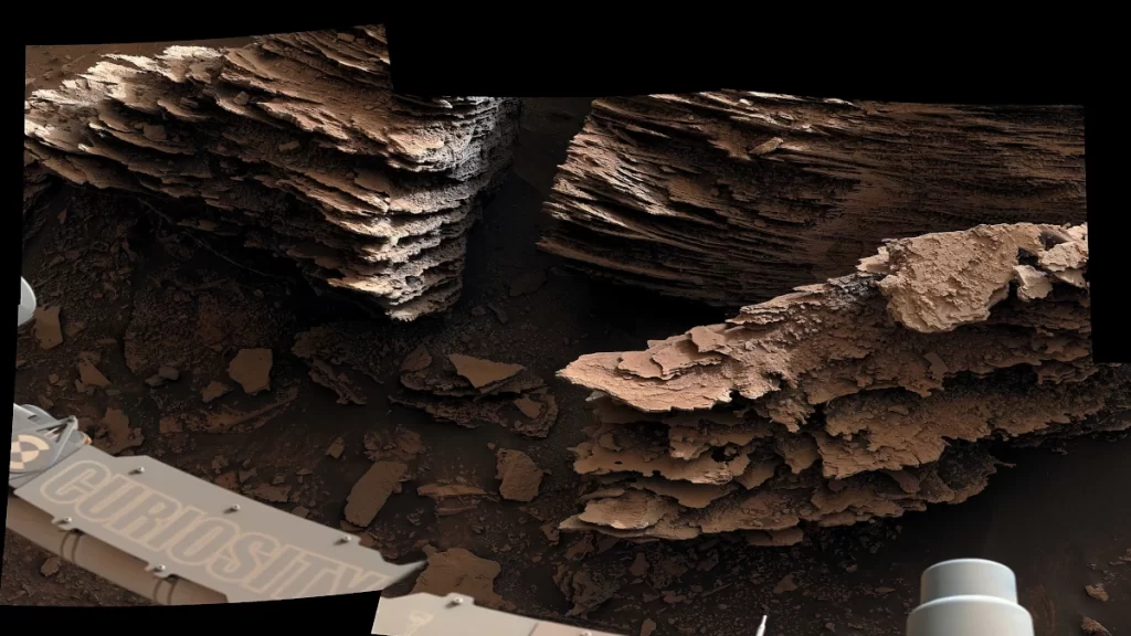 Il rover Curiosity della NASA ha catturato questa vista delle rocce stratificate che si ritiene si siano formate in un antico letto di un torrente o in un piccolo stagno. Le sei immagini che compongono questo mosaico sono state catturate utilizzando la Mastcam, il 2 giugno 2022, il 3.492esimo giorno marziano (sol) della missione. 